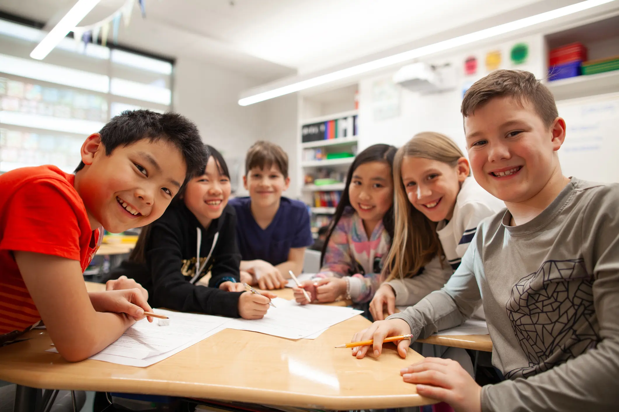 Portrait of group of multiracial elementary school students talking and enjoying studying together in a classroom